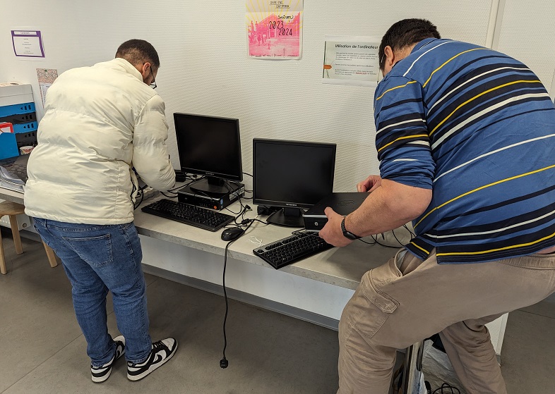 Deux personnes en train d'installer des ordinateurs sur une table