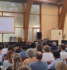 Une présentation se déroule devant un public nombreux et attentif, réuni dans une salle conviviale autour d’un intervenant et d’un écran de projection.